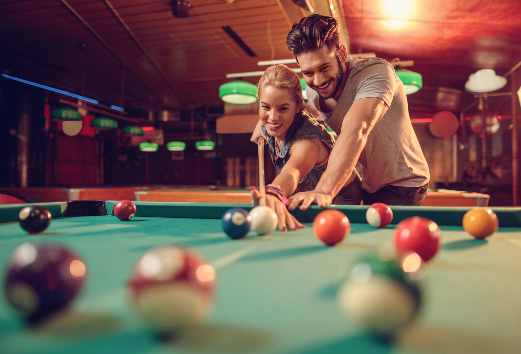 Young happy couple enjoying in a billiard game together.