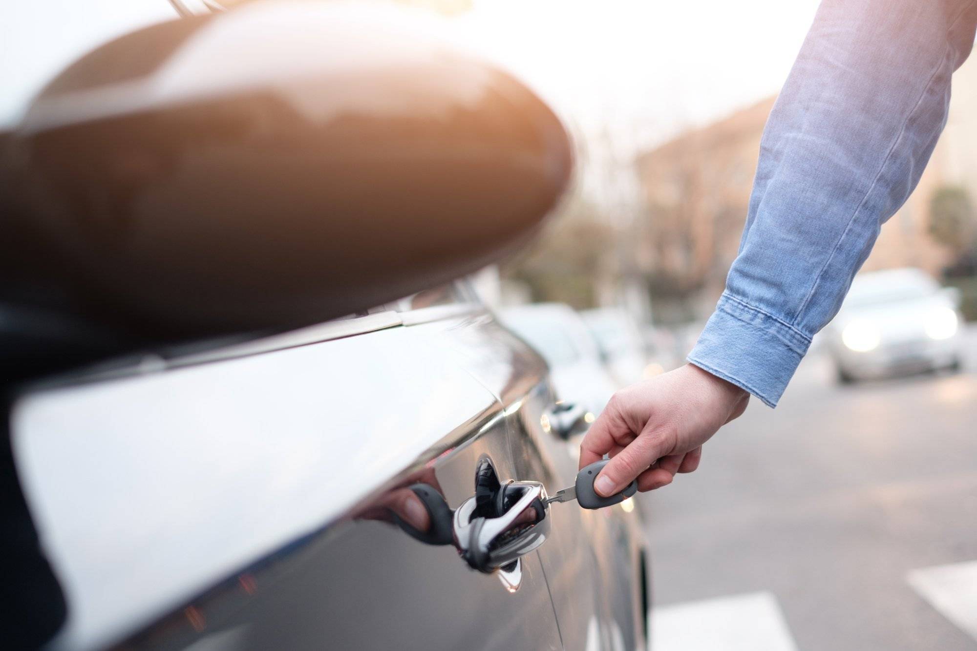 Hand holding a car key and opening the car door Hand holding a car key and opening the car door