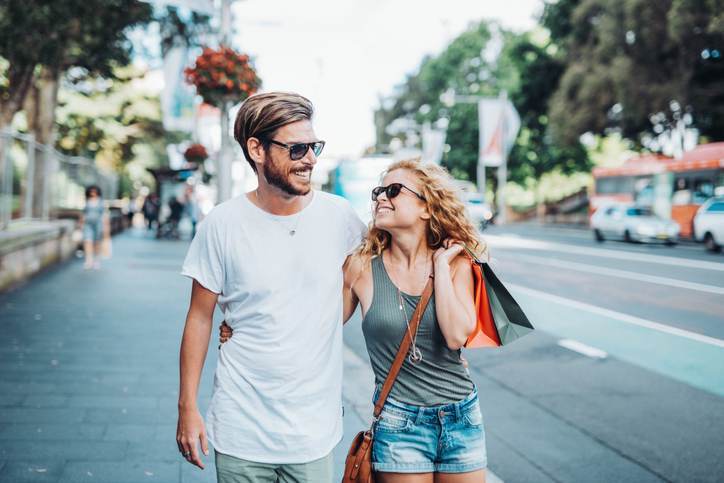 Cheerful couple with shopping bags and Christmas gifts in summer time