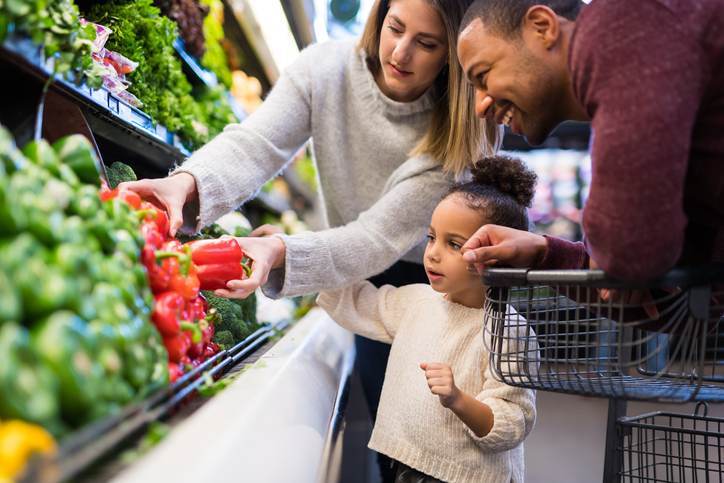 Mixed race couple grocery shopping with their preschool-age daughter