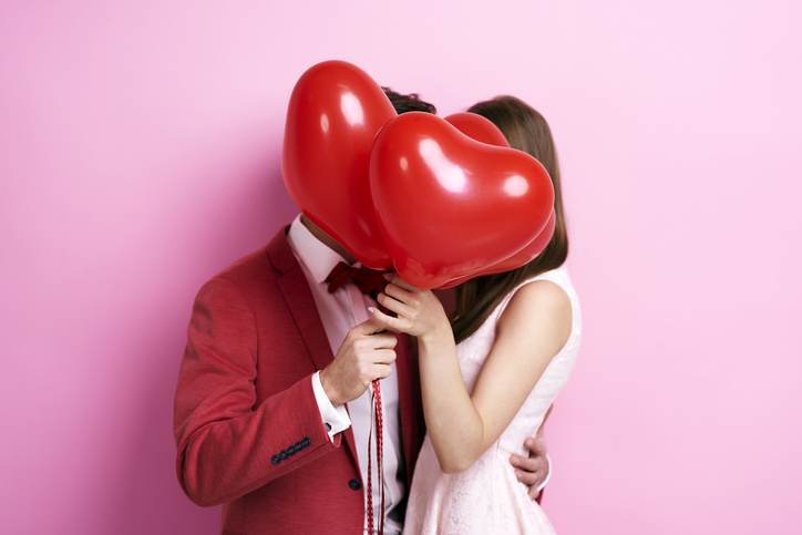 Couple kissing behind balloons