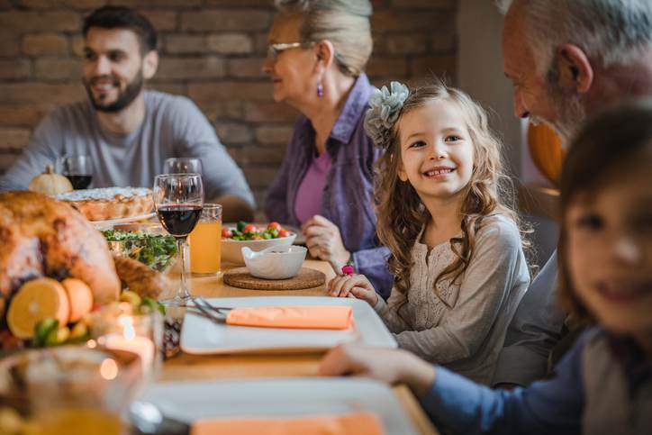 Happy girl talking to her grandfather during dinner at dining table.